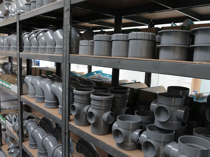 Large grev industrial PVC fittings on shelves in a plumbing supply warehouse