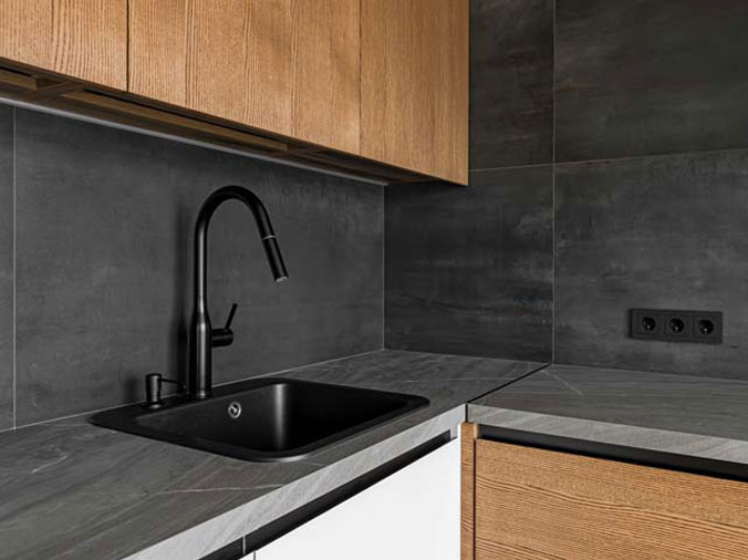 Black kitchen sink and faucet and dark grey countertops